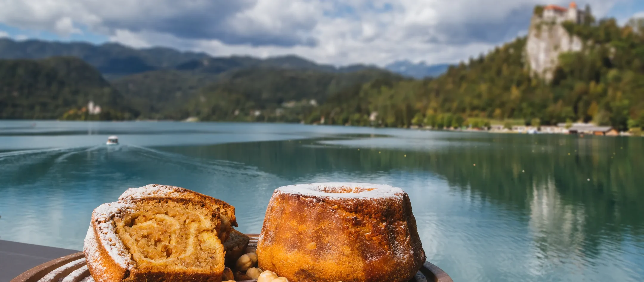 Potica and local pastries on a board by Lake Bled, the castle above