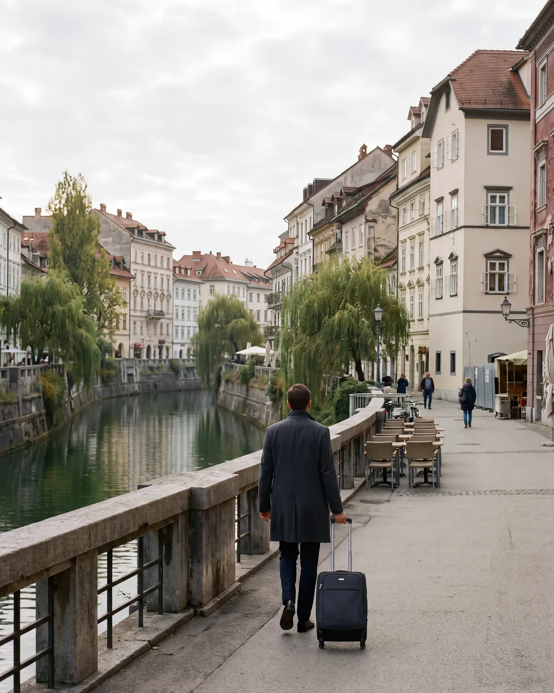 A business traveller walking the Ljubljanica embankment with a cabin case