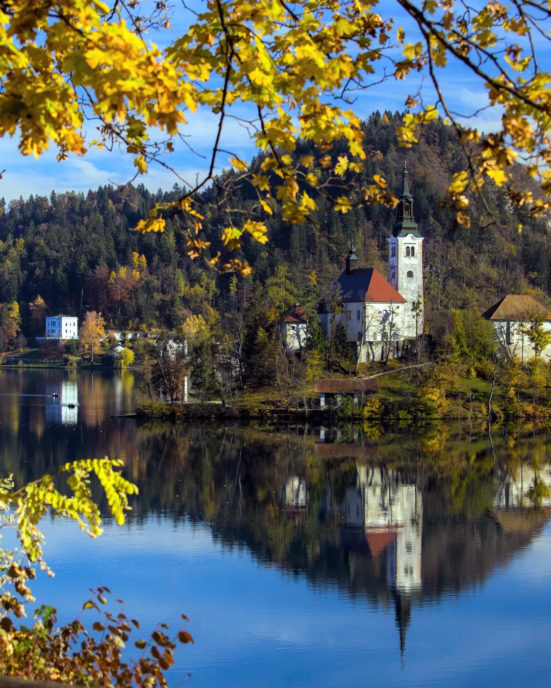 Bled Island framed by autumn leaves, mirrored in the lake